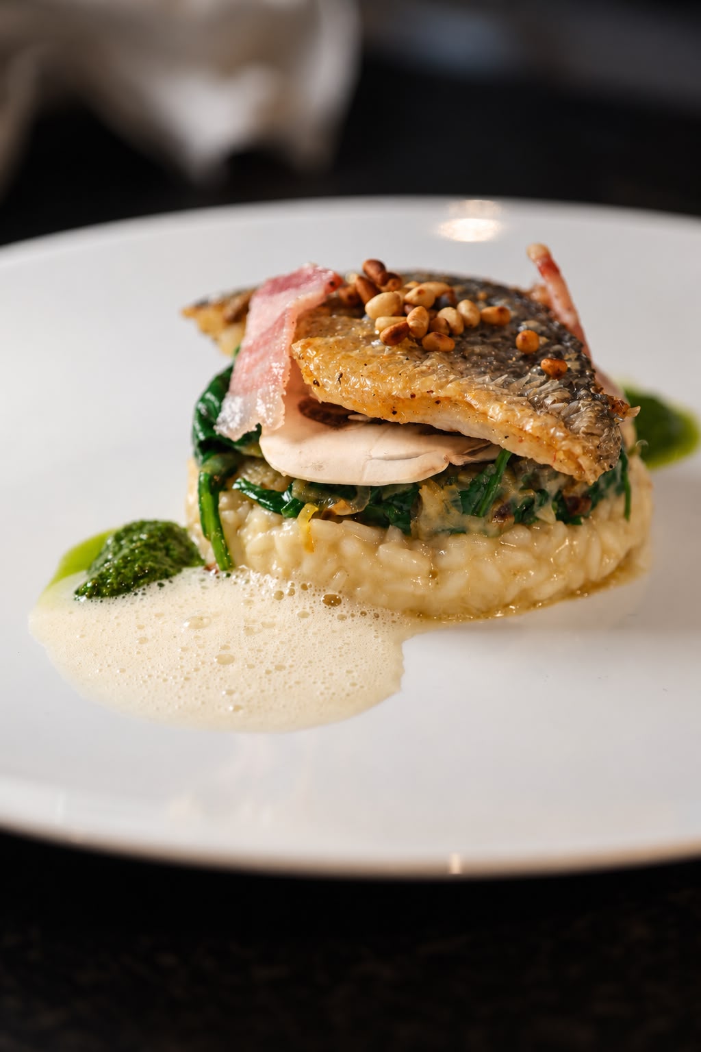 Geschmorter Fisch auf Risotto mit Spinat und Speck — Gericht aus der Küche des Kochwerk Berlin